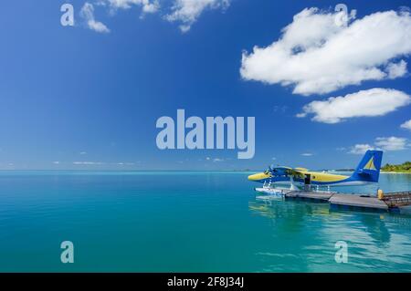 Blaues und gelbes Wasserflugzeug auf der türkisfarbenen maledivischen Lagune. Luxuriöses Reisekonzept Stockfoto