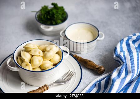 Schüssel mit russischen Pelmeni-Knödeln mit saurer Rahm und Petersilie Stockfoto