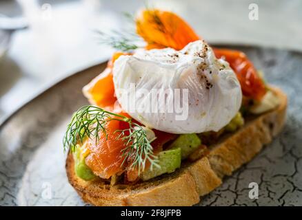 Lachsbruschetta mit Avocado und pochiertem Ei Stockfoto