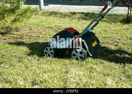 Belüftung mit einem Vertikutierer. Mit einem Scarifier im Garten zur Verbesserung der Rasenqualität im Frühjahr. Ein Arbeiter, Gärtner Betrieb Bodenbelüftung Stockfoto