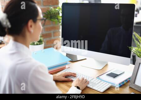 Junge Frau, die in der Nahaufnahme des Büros auf der Computertastatur tippt Stockfoto