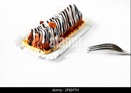 Nougatkuchen mit ausgefallenen gestreiften Topping Lines und Mandel auf weißem Hintergrund mit Gabel, süßes Dessert. Stockfoto