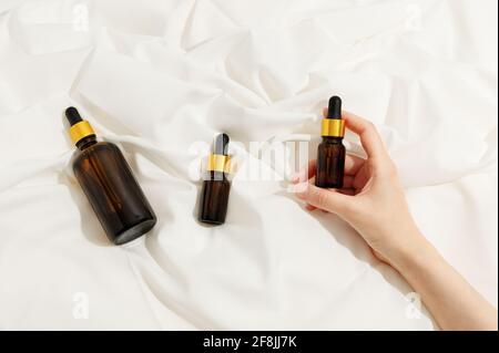 Die Hand der Frau hält Flaschen mit ätherischem Öl. Aromatherapie, natürlich Stockfoto