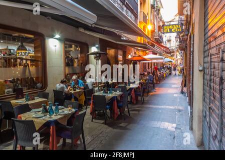 VALENCIA, SPANIEN, 17. JUNI 2019: In einer engen Straße im Zentrum von Valencia, Spanien, essen die Menschen Stockfoto