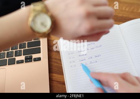 Frau zeigt mit Stift, um Liste für heute und zu tun Blick auf die Uhr aus der Nähe Stockfoto