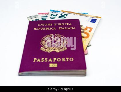 Italienischer Reisepäss mit einigen Euro-Banknoten isoliert auf weißem Hintergrund. Europäische Union und einheitliche Währung. Reisen und Bargeld Stockfoto