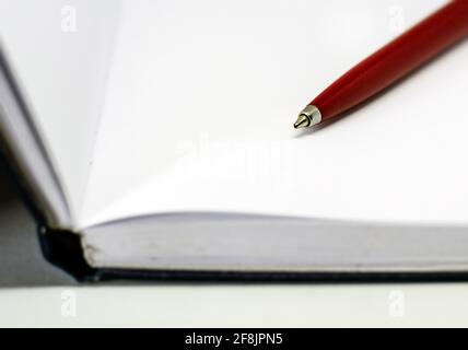 Roter Kugelschreiber auf den leeren weißen Seiten eines offenen Notizbuchs. Inspiration und Storytelling. Stockfoto