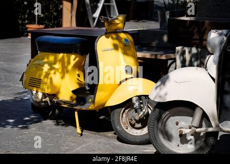 Ein klassischer, leuchtend gelber, ikonischer Vespa Motorroller, der auf einer Straße in der Altstadt von Rhodos auf der Insel Rhodos, Griechenland, geparkt ist Stockfoto