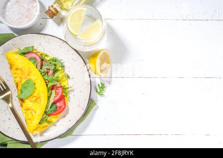 Frühling gesunde Ernährung Lebensmittelkonzept. Rühreier, gefülltes Omelett mit frischem Gemüse, Tomaten, Rucolla, Salat, auf weißem Hintergrund Platz zum Kopieren Stockfoto