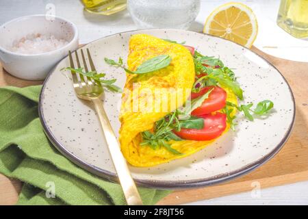 Frühling gesunde Ernährung Lebensmittelkonzept. Rühreier, gefülltes Omelett mit frischem Gemüse, Tomaten, Rucolla, Salat, auf weißem Hintergrund Platz zum Kopieren Stockfoto