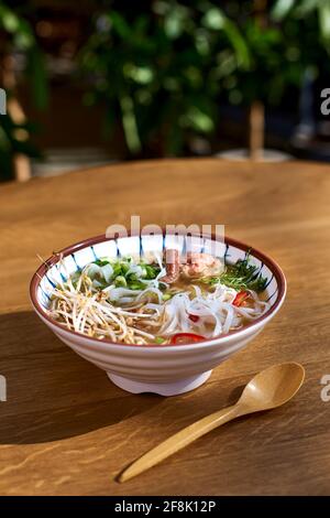 Asiatische Pho bo-Suppe, beste Pho-Brühe, in einer leichten Schüssel auf einem Holztisch. Kopierbereich, selektiver Fokus Stockfoto