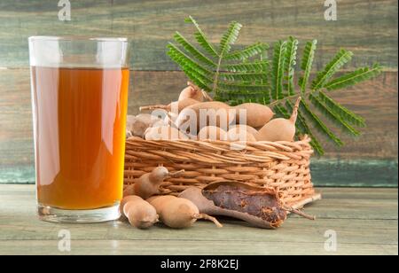 Tamarindensaft in einem Glas, umgeben von frischen reifen Tamarinden - Tamarindus indica Stockfoto