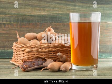 Tamarindensaft in einem Glas, umgeben von frischen reifen Tamarinden - Tamarindus indica Stockfoto