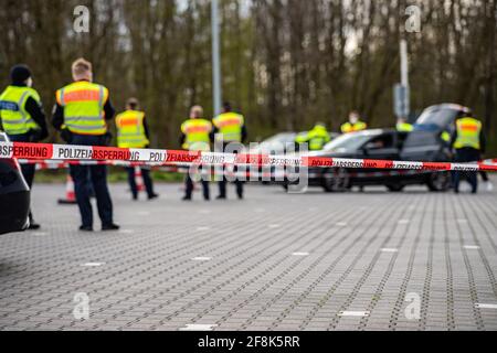 Bad Bentheim, Deutschland. April 2021. Bundespolizisten stehen hinter einer Schranke und kontrollieren kurz nach der deutsch-niederländischen Grenze auf einem Parkplatz auf der A 30 mehrere Fahrzeuge. Die Bundespolizei führt gemeinsam mit ihren Kollegen der Niedersächsischen Landespolizei einen Großscheck an der A 30 an der deutsch-niederländischen Grenze durch. Der Schwerpunkt der groß angelegten Kontrolloperation liegt auf der Bekämpfung der grenzüberschreitenden Kriminalität. Quelle: Guido Kirchner/dpa/Alamy Live News Stockfoto