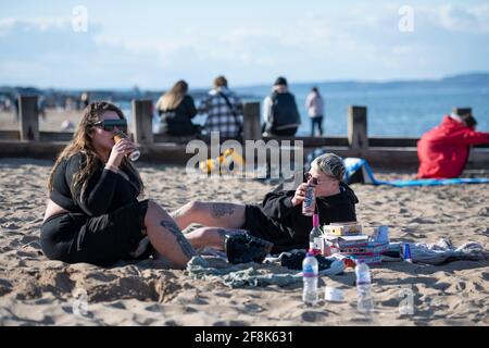 Edinburgh, Schottland, Großbritannien. April 2021. IM BILD: Leute, die sich am Portobello Beach Vergnügen. Die Menschen genießen den klaren blauen Himmel und das warme, sonnige Wetter auf der Ostseite Schottlands am Portobello Beach. Quelle: Colin Fisher/Alamy Live News Stockfoto