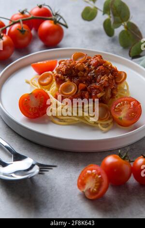 Spaghetti mit Tomatensauce und Wurst in weißem Teller auf dem Tisch Stockfoto