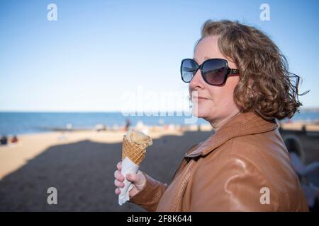 Edinburgh, Schottland, Großbritannien. April 2021. IM BILD: Eine Person genießt einen Eiskegel am Portobello Beach. Die Menschen genießen den klaren blauen Himmel und das warme, sonnige Wetter auf der Ostseite Schottlands am Portobello Beach. Quelle: Colin Fisher/Alamy Live News Stockfoto