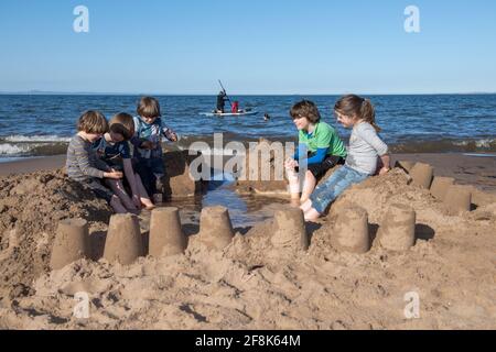 Edinburgh, Schottland, Großbritannien. April 2021. IM BILD: Kinder bauen Sandburgen und spielen im Sand am Portobello Beach. Die Menschen genießen den klaren blauen Himmel und das warme, sonnige Wetter auf der Ostseite Schottlands am Portobello Beach. Quelle: Colin Fisher/Alamy Live News Stockfoto