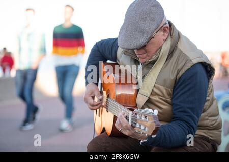 Edinburgh, Schottland, Großbritannien. April 2021. IM BILD: Auf der Promenade am Portobello Beach spielt ein Straßenkünstler vor Zuschauern die akustische Gitarre. Die Menschen genießen den klaren blauen Himmel und das warme, sonnige Wetter auf der Ostseite Schottlands am Portobello Beach. Quelle: Colin Fisher/Alamy Live News Stockfoto