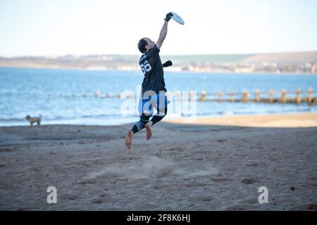 Edinburgh, Schottland, Großbritannien. April 2021. IM BILD: Ein Mann fängt eine fliegende Frisbee am Strand von Portobello. Die Menschen genießen den klaren blauen Himmel und das warme, sonnige Wetter auf der Ostseite Schottlands am Portobello Beach. Quelle: Colin Fisher/Alamy Live News Stockfoto