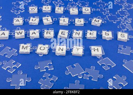 Hintergrund des Welt-Autismus-Bewusstseins-Monats. Transparente Puzzle Details auf Inschrift auf blauem Hintergrund. Stockfoto