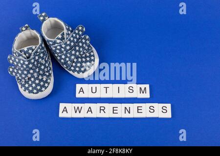 Hintergrund des Autismus-Bewusstseins. Kinder-Jeans-Sportschuhe mit Aufschrift Autismus Awareness auf blauem Hintergrund. Flach liegend. Speicherplatz kopieren. Stockfoto