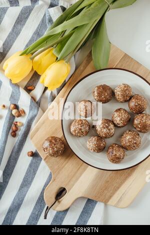 Schokoladenkuchen, serviert auf einem Teller auf einem Holztablett mit gelber Tulpe. Stockfoto