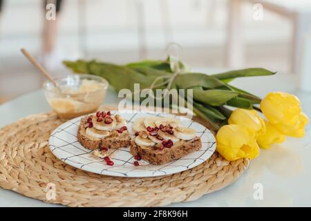 Schuss der Erdnussbutter Toast mit Früchten auf einem Teller mit gelben Tulpe verziert. Stockfoto