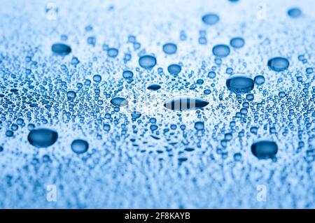 Nahaufnahme Tropfen Wasser auf glänzendem Hintergrund. Blaues Bild. Flacher Freiheitsgrad Stockfoto