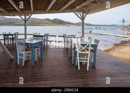 Antiparos, Griechenland - 28. September 2021: Tische und Stühle im griechischen Restaurant am Meer auf der Insel Antiparos. Kykladen, Griechenland Stockfoto