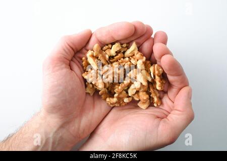 Hände halten einen Haufen Walnusskerne auf weißem, isoliertem Hintergrund. Draufsicht. Stockfoto
