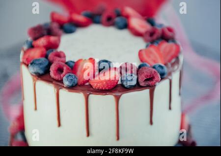 Schokoladenkuchen mit Schlagsahne und frischen Beeren. Nahaufnahme. Biskuitkuchen mit Erdbeeren und Vanillecreme. Stockfoto