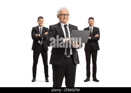 Reifer Geschäftsmann mit einem Laptop und zwei männlichen Kollegen hinter sich Isoliert auf weißem Hintergrund Stockfoto