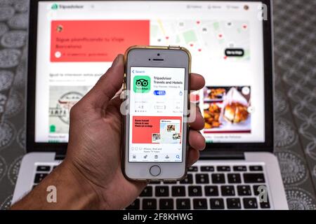 Barcelona, Katalonien, Spanien. April 2021. In dieser Abbildung wird die TripAdvisor-App im App Store auf einem Smartphone-Bildschirm mit einer TripAdvisor-Website auf einem Laptop im Hintergrund angezeigt. Quelle: Thiago Prudencio/DAX/ZUMA Wire/Alamy Live News Stockfoto