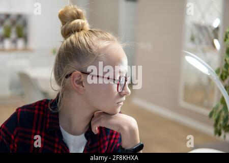 Blonde Mädchen mit Brille arbeiten auf einem Laptop. Home-School-Konzept Stockfoto