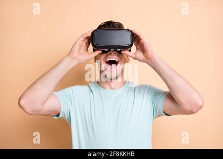 Nahaufnahme Porträt von netten fröhlichen Kerl zu beobachten trägt vr Helm Spaß isoliert über beige Pastellfarben Hintergrund Stockfoto