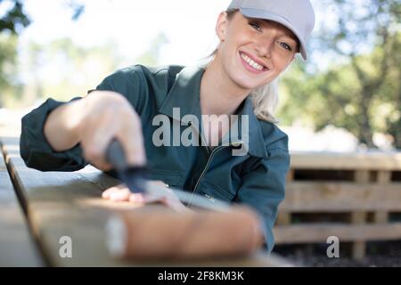 Attraktive junge Frau, die im Freien einen Tisch malt Stockfoto