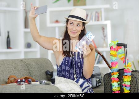 Frau, die ein Selfie von sich selbst macht, indem sie Pässe und Reisetickets hält Stockfoto