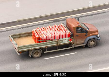 LKW-Ladung von roten Gasflaschen und fährt auf dem autobahn Stockfoto