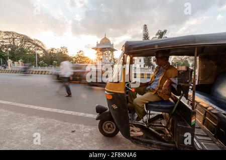 Mysuru, Karnataka, Indien - 2019. Januar: Ein Rikscha-Fahrer an einem geschäftigen Kreisverkehr in der Stadt Mysore mit Sonnenuntergang. Stockfoto