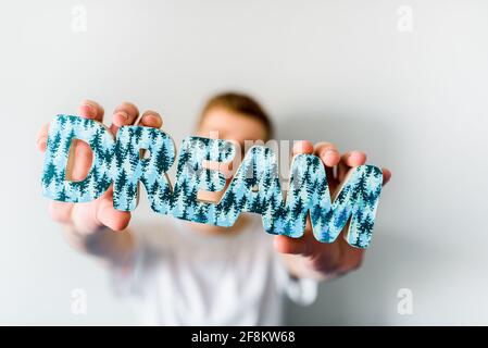 Porträt eines jungen Mannes auf der blauen Couch. Die Inschrift in den Händen - Träume Stockfoto
