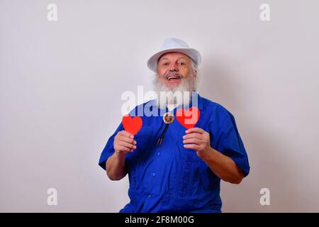 Reifer Herr feiert Valentinstag mit zwei roten Papierherzen Stockfoto