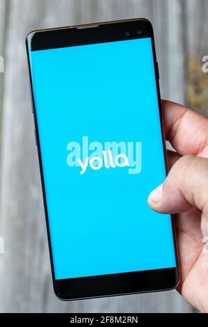 Ein Mobiltelefon oder Mobiltelefon, das in einem gehalten wird Hand zeigt die Yolla App auf dem Bildschirm Stockfoto