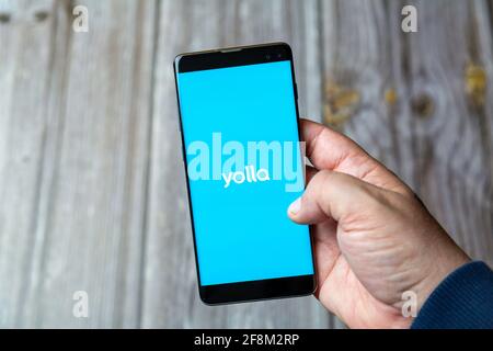 Ein Mobiltelefon oder Mobiltelefon, das in einem gehalten wird Hand zeigt die Yolla App auf dem Bildschirm Stockfoto