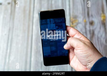 Ein Mobiltelefon oder Mobiltelefon, das in einem gehalten wird Hand zeigt die SlideShare-App auf dem Bildschirm Stockfoto