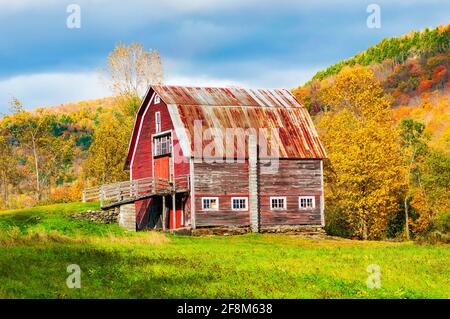 Alte verblasste rote Scheune am Straßenrand in den Green Mountains der Adirondack-Kette, Vermont, USA. In Der Nähe Von Hancock, Vermont. Stockfoto