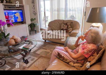 93-jährige verwitwete Frau, die allein zu Hause sitzt und einen gewissen Verlust an kognitivem Gedächtnis hat und fernsieht. Stockfoto