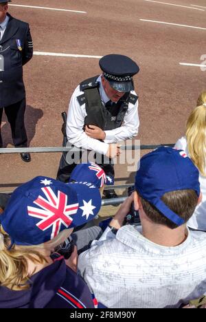 Sergeant Polizist in London, Großbritannien, interagiert mit australischen Touristen in der Mall, während sie während des Trooping the Color auf die Prozession warten Stockfoto