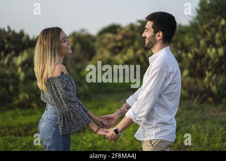 Glückliches junges Paar, das die Hände hält und sich anschaut Stockfoto