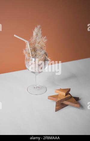 Pampas Gras Cocktail in einem Glas mit einem Stroh aus Pampastiel. Minimale abstrakte Komposition Hintergrund. Japanische Inneneinrichtung. Erfrischungsidee. Stockfoto